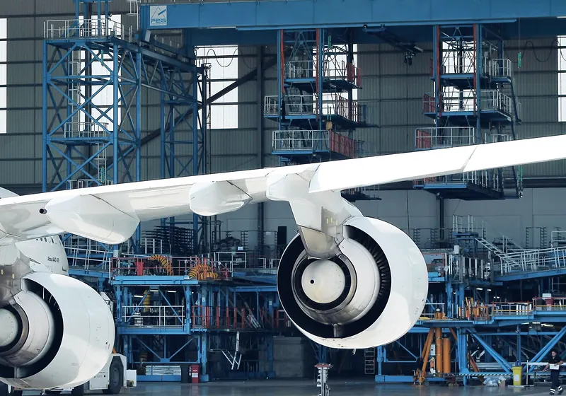Wing and two engines of a wide-body airliner inside a maintenance hangar