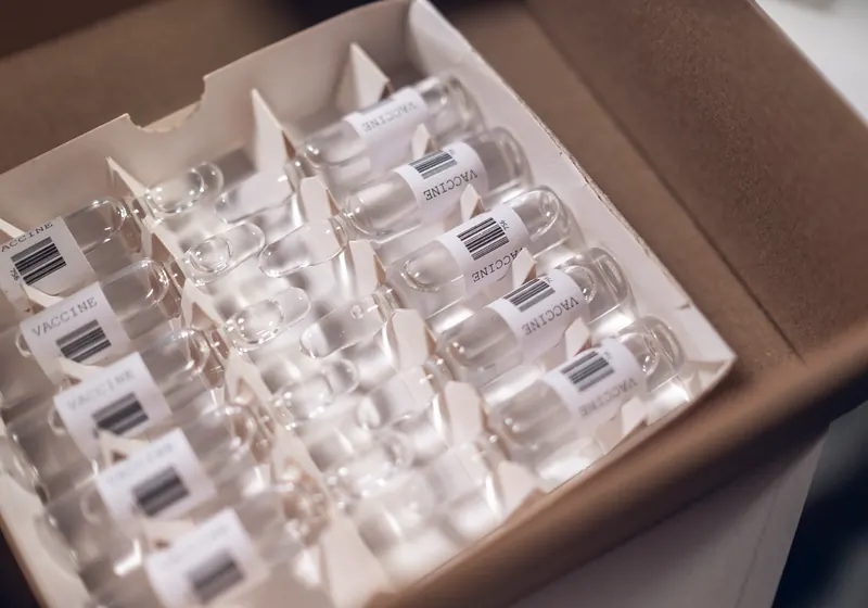 Glass vials with barcode labels packed upright in a cardboard tray